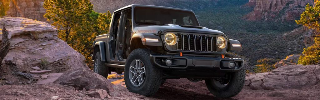 Jeep Gladiator off-roading on rocky terrain with open doors, showcasing its rugged capability and adventurous design.